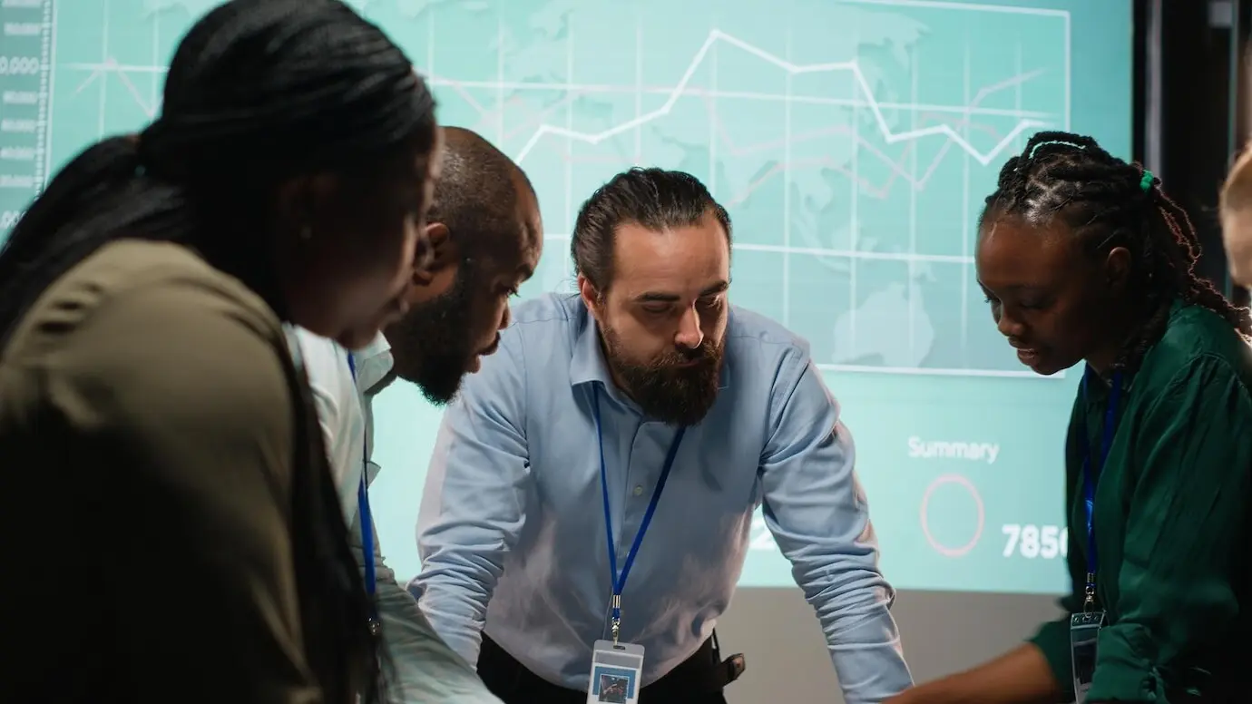 Разнообразные коллеги присутствуют на деловой встрече после рабочего времени для анализа файлов.